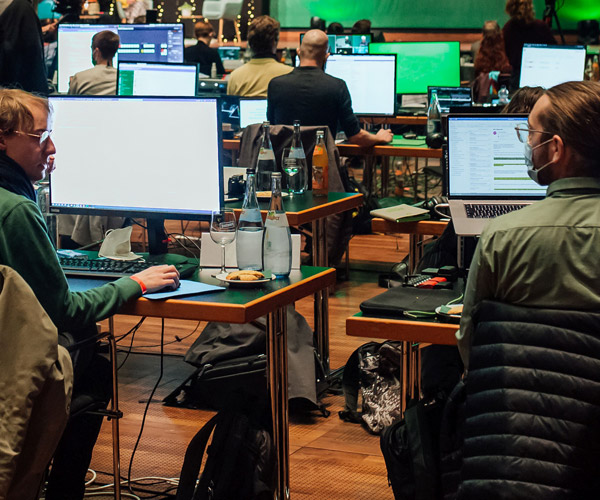 Bild eines Hackathon mit vielen Monitoren auf Tischen